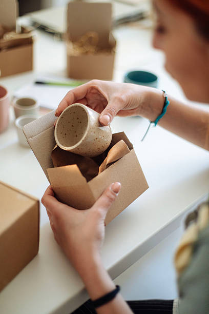 istock female ceramic artist packing handmade mugs in studio 2245973815
