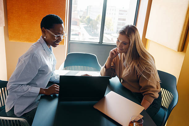 istock Two women discussing project ideas at a table in a modern office 2245976303