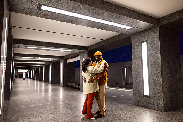 A young mixed-race couple, with the man being Black and the woman white, share a joyful moment in a modern Berlin metro station. The couple is dressed casually and appears to be enjoying their time together, showcasing the vibrant atmosphere of the city.