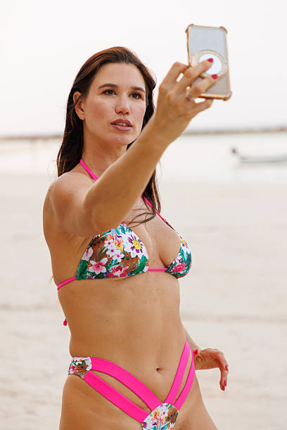istock Woman in a bikini taking a selfie on a scenic beach 2245977749