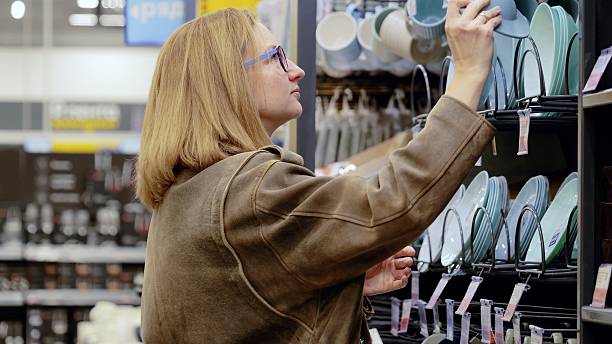 istock Customer carefully selecting pastel colored dishware from a shelf in a home goods store, making decisions for their kitchen 2245981025