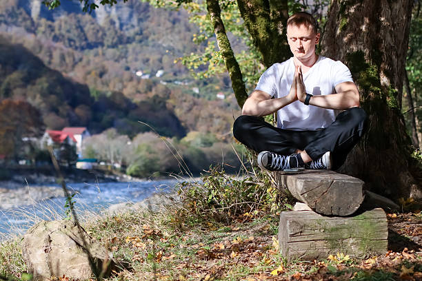 istock Man in namaste pose meditating by river in autumn 2245984004