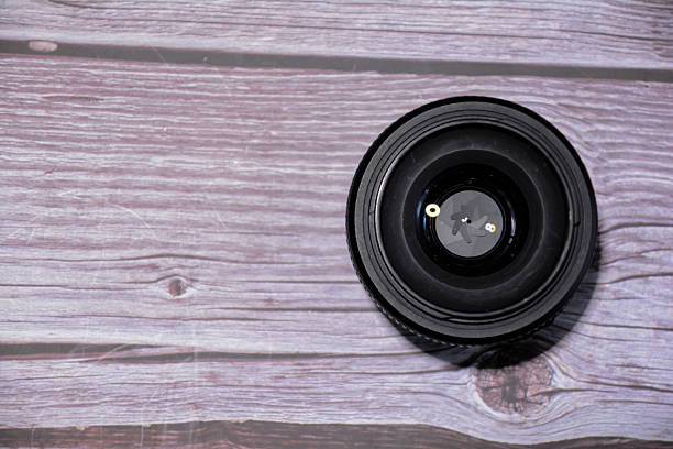 istock Camera lens on a wooden background. Black lens and lens cap 2245984145