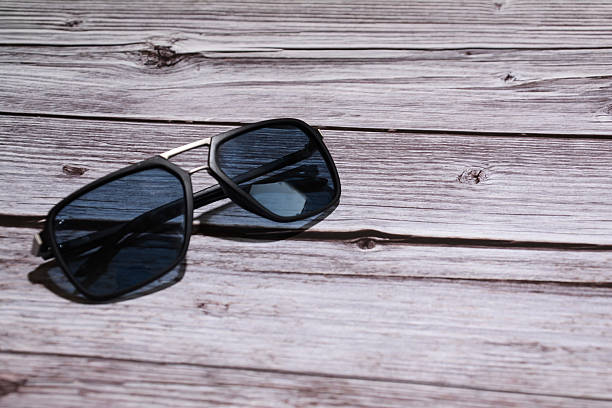 istock Sunglasses on wooden background. Black sunglasses 2245984230
