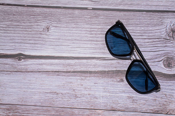 istock Sunglasses on wooden background. Black sunglasses 2245984234