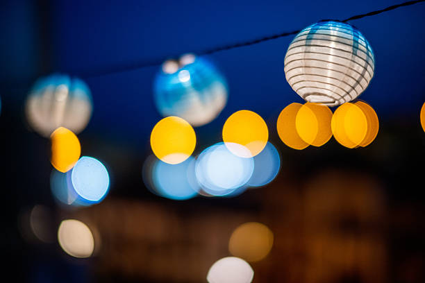 Softly glowing paper lanterns create a warm atmosphere on a terrace for a nighttime celebration, casting light in the dark with dreamy effects.