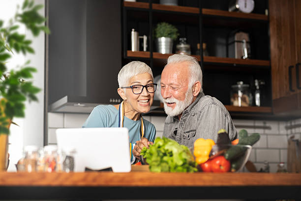istock Senior couple cooking together in kitchen using laptop 2245986461
