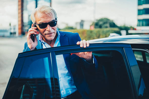 istock Businessman talking on smartphone while getting out of car 2245988112