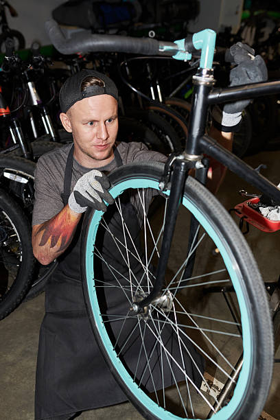 istock Young Man Repairing Bicycle Wheel in Workshop Setting 2245988226