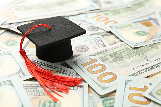 istock Scholarship. Graduate hat on dollar banknotes, closeup. Space for text 2245989731