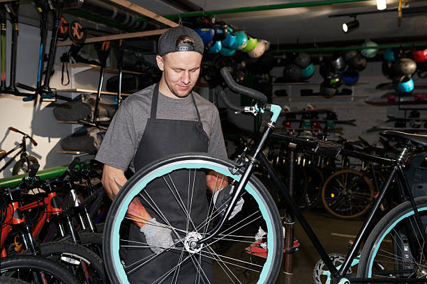 istock Young Man Polishing Bicycle Wheel during Workshop Maintenance 2245990088