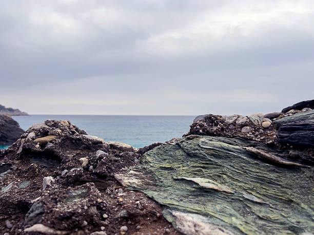 Coastal rock formation with overcast sky and ocean horizon.