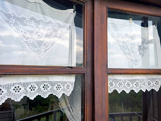 istock Lace curtains on wooden window reflecting sky and landscape 2245990186