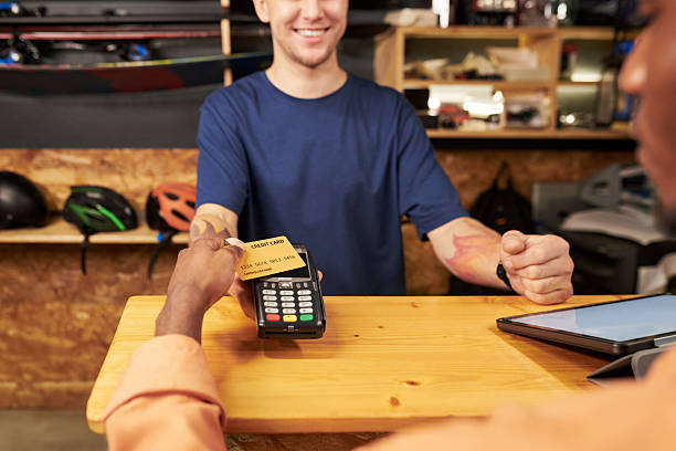 istock Young Man Smiling While Accepting Credit Card Payment at Counter 2245990415