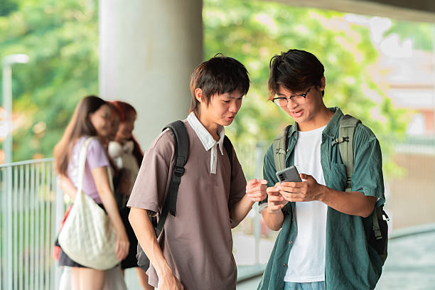 istock Asian smiling college students using smart phone at pathway stock photo 2245990891
