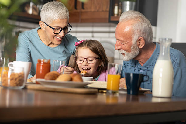 istock Happy girl surrounded with grandparents during breakfast 2245992536