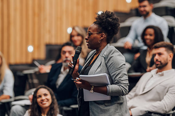 istock Woman speaking into microphone during corporate conference 2245992542