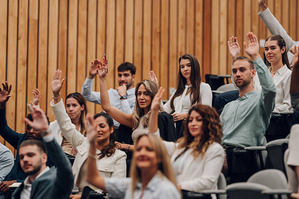 istock Audience raising hands participating in a conference presentation 2245993106