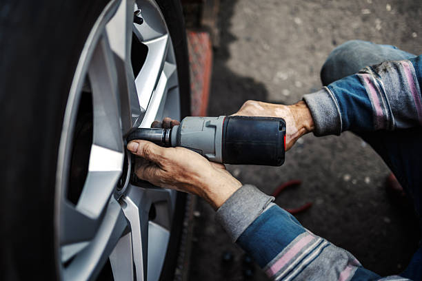istock Mechanic changing car tire using pneumatic impact wrench 2245994402