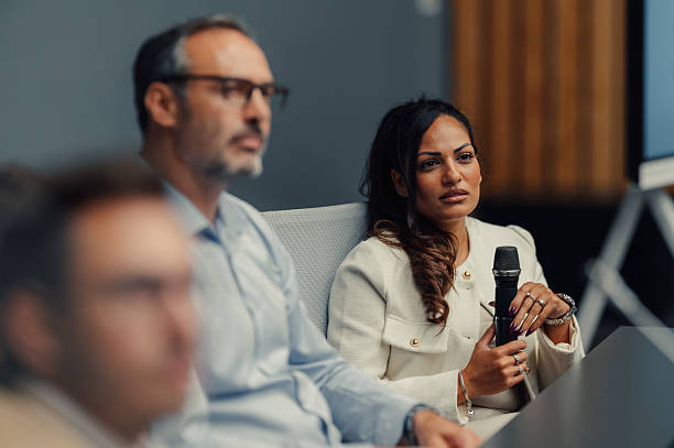 istock Businesswoman holding microphone during conference or seminar 2245994911