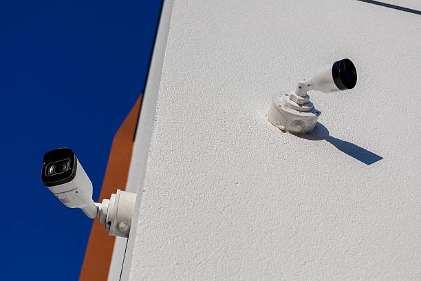 istock Two security cameras are installed on a white wall, providing surveillance and protection in a clear sky setting 2245995278