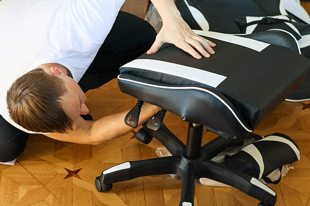 istock Man fine-tuning chair controls while kneeling beside assembled seat. 2245997427