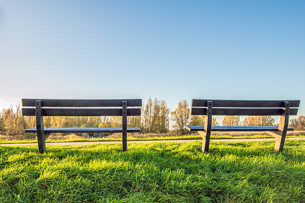 Two empty benches on top of a Dutch dike. The photo was taken at the end of a sunny autumn day.