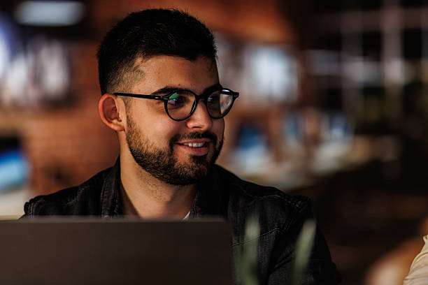 istock Young man smiling while working late at his desk 2246000003