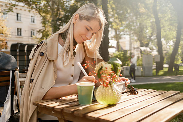 Woman enjoying outdoor cafe while writing in a notebook on a sunny day
