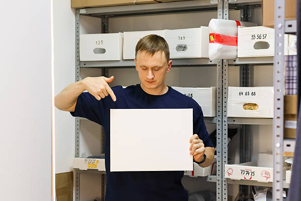 istock Man gesturing down to held blank paper near racks 2246002732