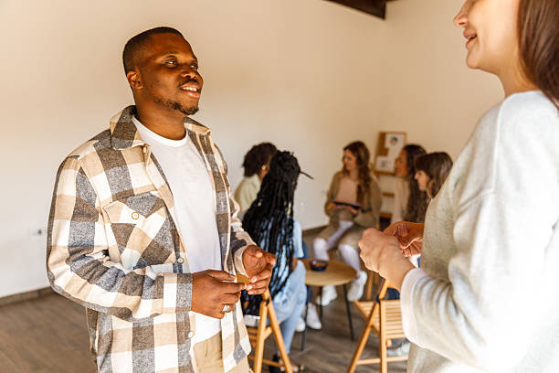 istock Young man confiding to a friend outside the circle during a group therapy session 2246002776