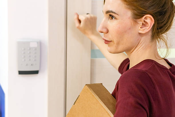 istock Woman holding package pushes door by keypad 2246002805