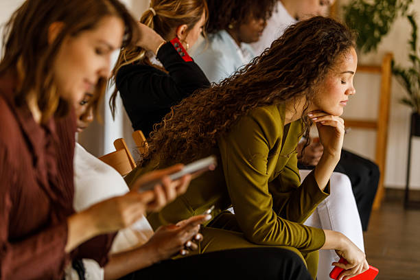 istock Group of people sitting in line, using their smart phones while waiting 2246002925
