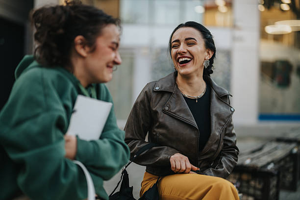 istock Two women laugh together outdoors in an urban setting, sharing a joyful moment 2246003088