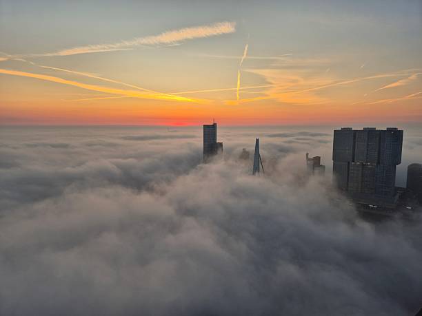 Downtown Rotterdam skyline over river Meuse seen from high angle with fog covering everything except the highest tips of the Erasmus bridge and top of skyscrapers