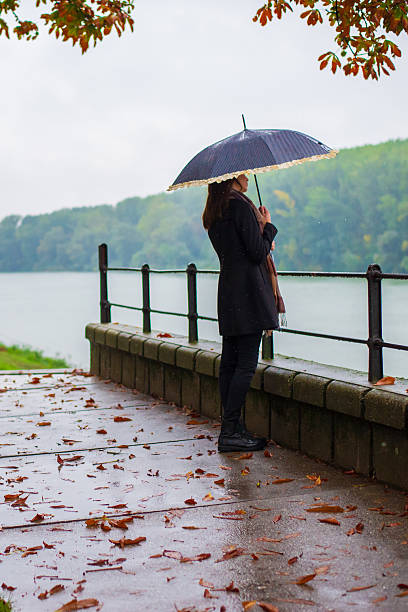 istock Woman with umbrella walking alone in the rain 2246004818