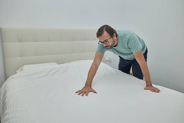 istock Man making the bed in a modern bedroom 2246005729