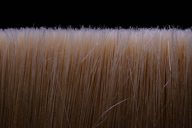 Creative brush with blonde hair instead of bristles on vivid pink background representing beauty and artistic hairstyling concept.