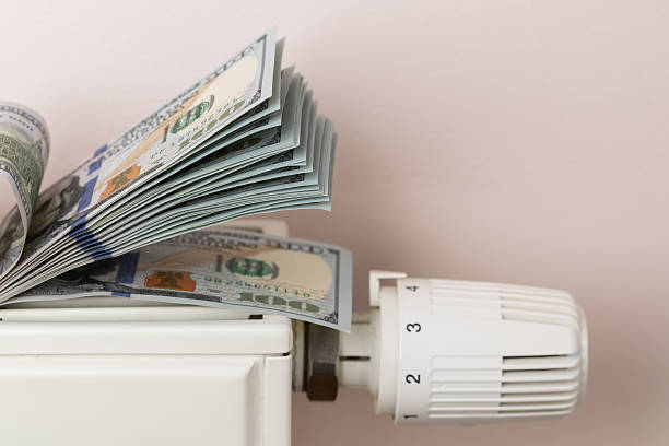 istock Money Stack on Heating Radiator Thermostat Symbolizing Cost 2246009783