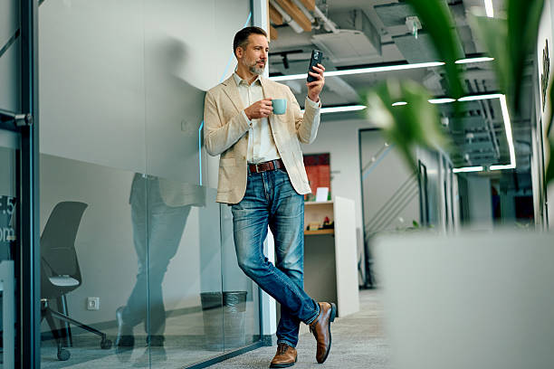 istock Businessman having coffee break and using smartphone in office 2246010420
