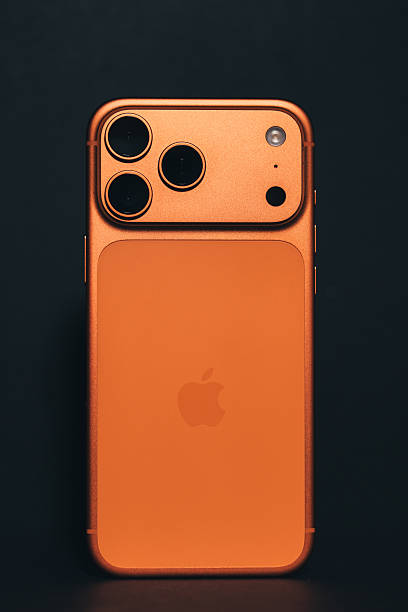 Krakow, Poland - November 6, 2025. The latest Apple iPhone 17 Pro Max in Cosmic Orange, featuring a bold triple camera design and the signature Apple logo, is seen in a pristine product photo against a black background. The editorial image highlights the iconic, innovative design and vibrant color option of Apple's flagship smartphone for 2025.