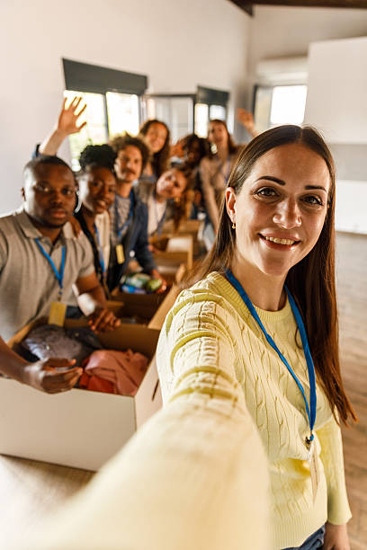 istock Group of diverse volunteers taking selfies together while preparing donations 2246010985