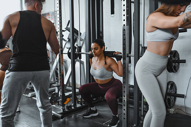 istock Group Gym Training Session With Focused Lifter Squatting While Teammates Work Out Nearby 2246011660
