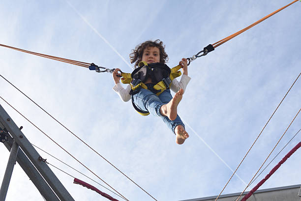 istock Child playing on a trampoline at an amusement park, looking at camra, 2246011752