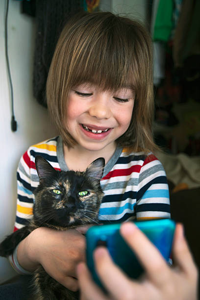 istock Child and cat using phone together in playful home scene 2246013609