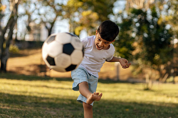 istock Excited boy kicking soccer ball outdoors on a sunny day 2246013679
