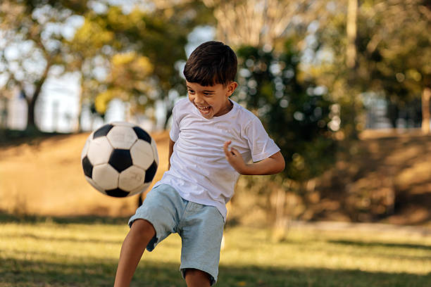 istock Excited boy kicking soccer ball outdoors on a sunny day 2246013714