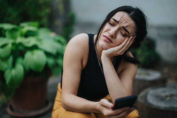 istock Tired woman outdoors rests her head on her hand while looking at her phone, conveying fatigue and distraction 2246020963
