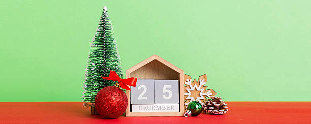 istock 25 december. Christmas composition on colored background with a wooden calendar, with a gift box, toys, bauble copy space 2246021387