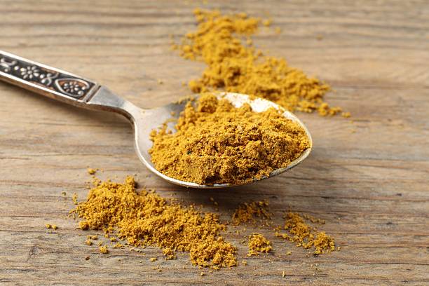 istock Spoon with dry curry powder on wooden table, closeup 2246022339